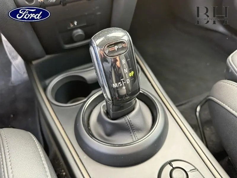 Le levier de vitesse automatique noir brillant de la MINI COUNTRYMAN Melting Silver III vu de dessus, avec console centrale en similicuir noir.