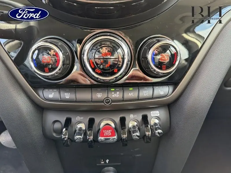 Gros plan sur la console centrale du MINI Countryman Melting Silver III 2023, avec commandes chromées et bouton start/stop rouge.