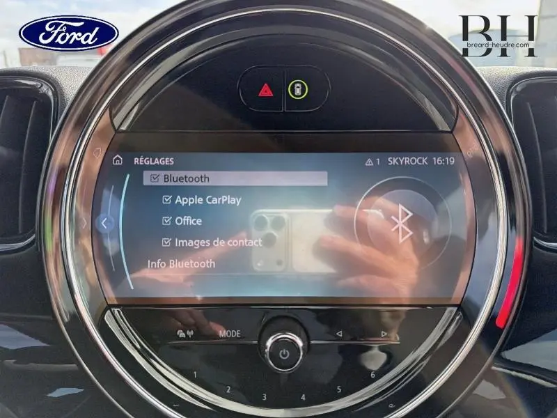 Vue rapprochée de l'écran tactile central rond du MINI Countryman Melting Silver III, affichant les réglages Bluetooth.