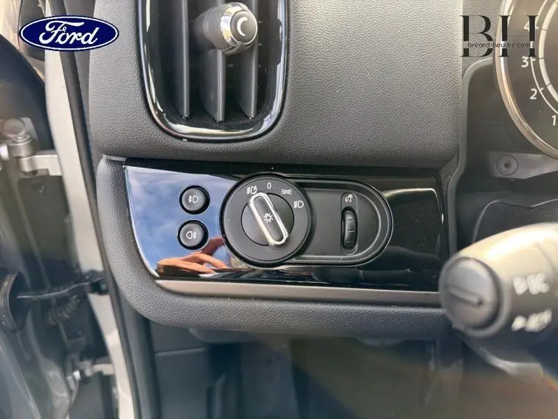 Gros plan sur le bouton de commande des phares du MINI Countryman Melting Silver III, intérieur noir brillant.