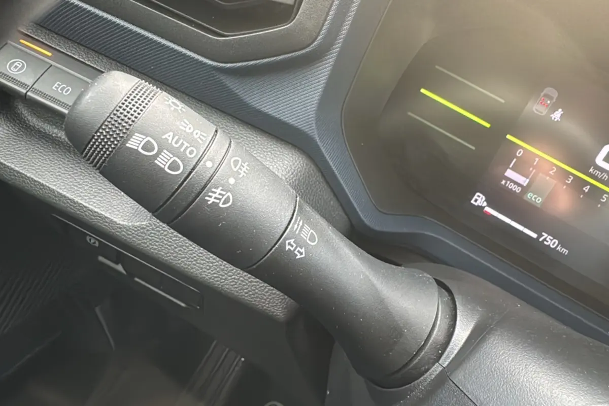 Gros plan sur la commande des phares et clignotants du tableau de bord du Dacia Duster 2025, intérieur noir.