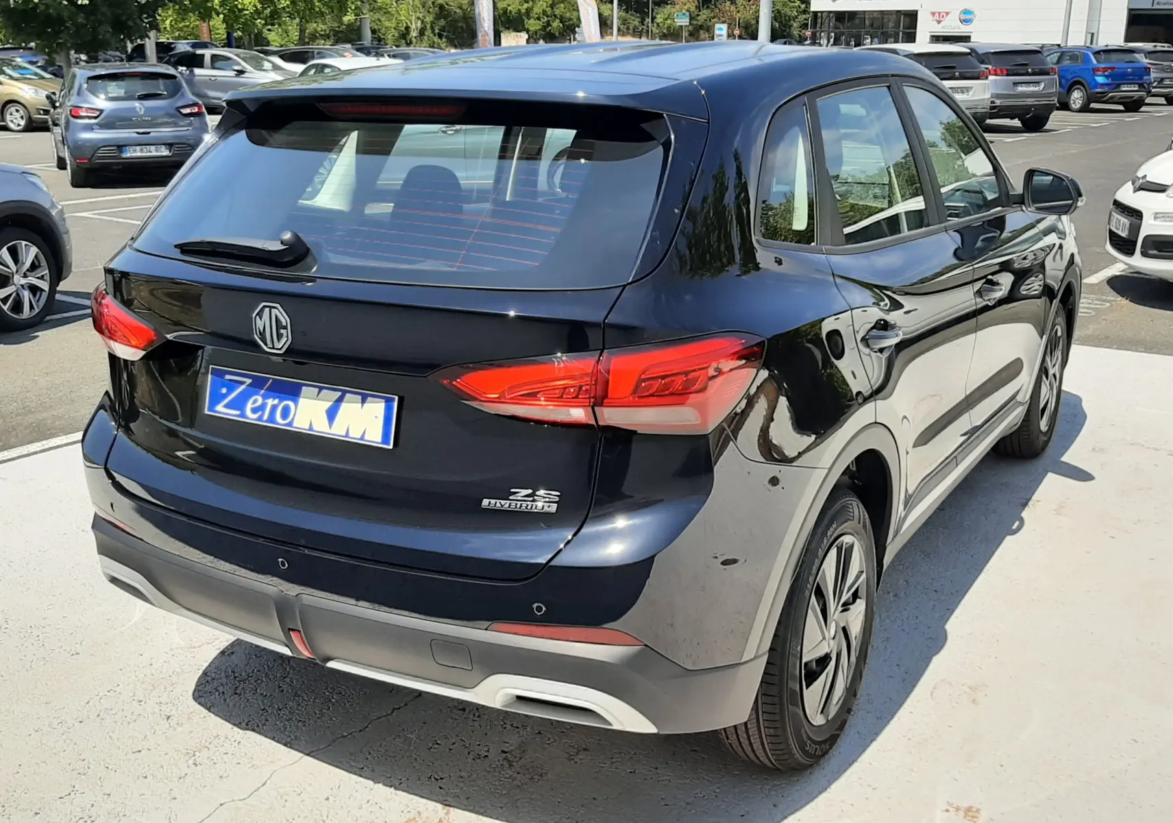 Vue 3/4 arrière droite d'un MG Motor ZS 1.5L Hybrid+ 197ch noir Pebble Black Metal, avec feux arrière LED et hayon fermé.