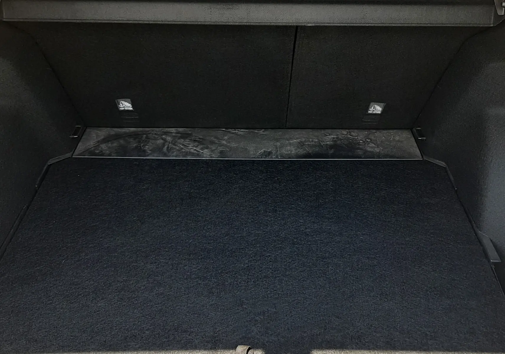 Coffre ouvert vu de face du MG Motor ZS 1.5L Hybrid+ 2026 en Pebble Black Metal, intérieur noir et tapis de sol.