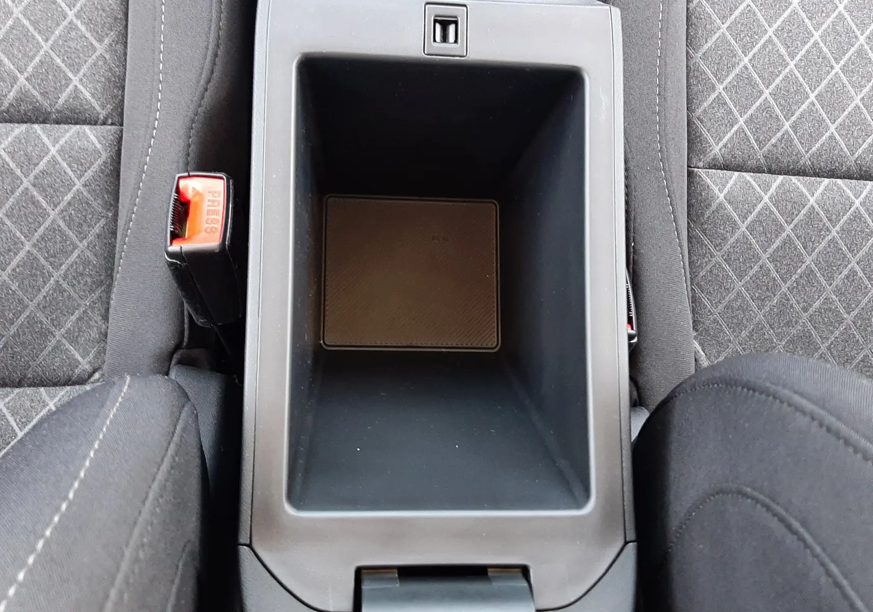 Vue plongeante sur la console centrale noire et les sièges en tissu gris à motifs du MG MOTOR ZS hybride 2026.