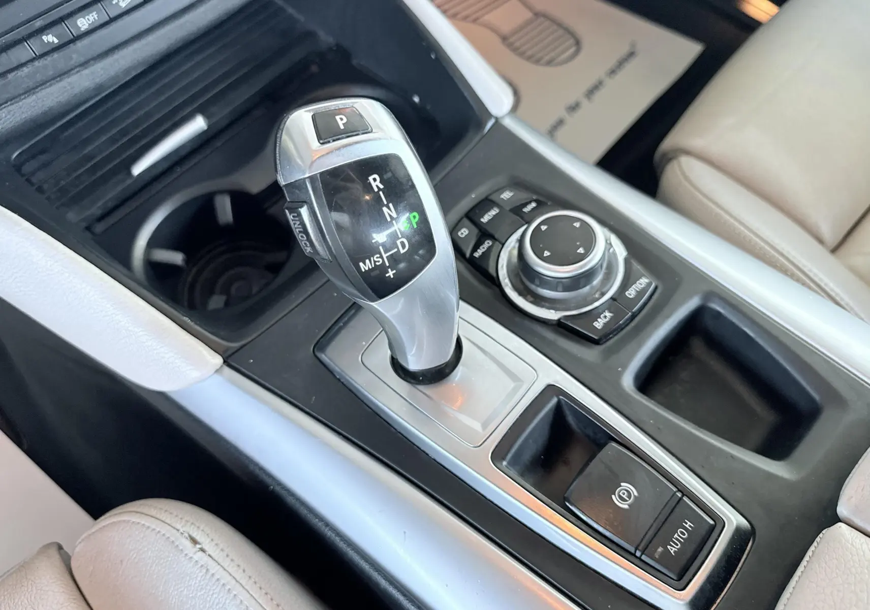 Gros plan sur la console centrale avec levier de vitesse automatique et commandes du BMW X6 noir, intérieur cuir beige.