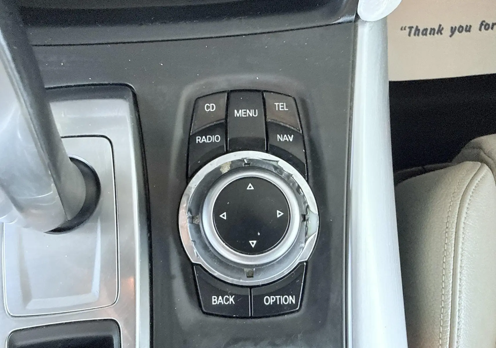 Gros plan sur la molette de commande centrale du système multimédia d'une BMW X6 noire, avec boutons fonctionnels visibles.