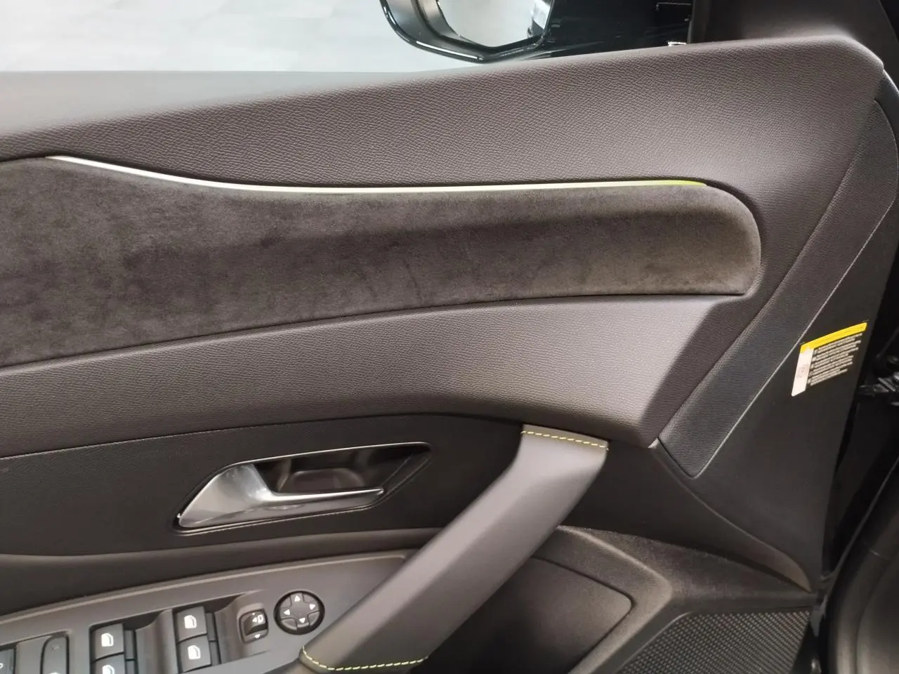 Détail de la porte avant gauche de la Peugeot 308 noire, avec surpiqûres vert Adamite et insert en alcantara.