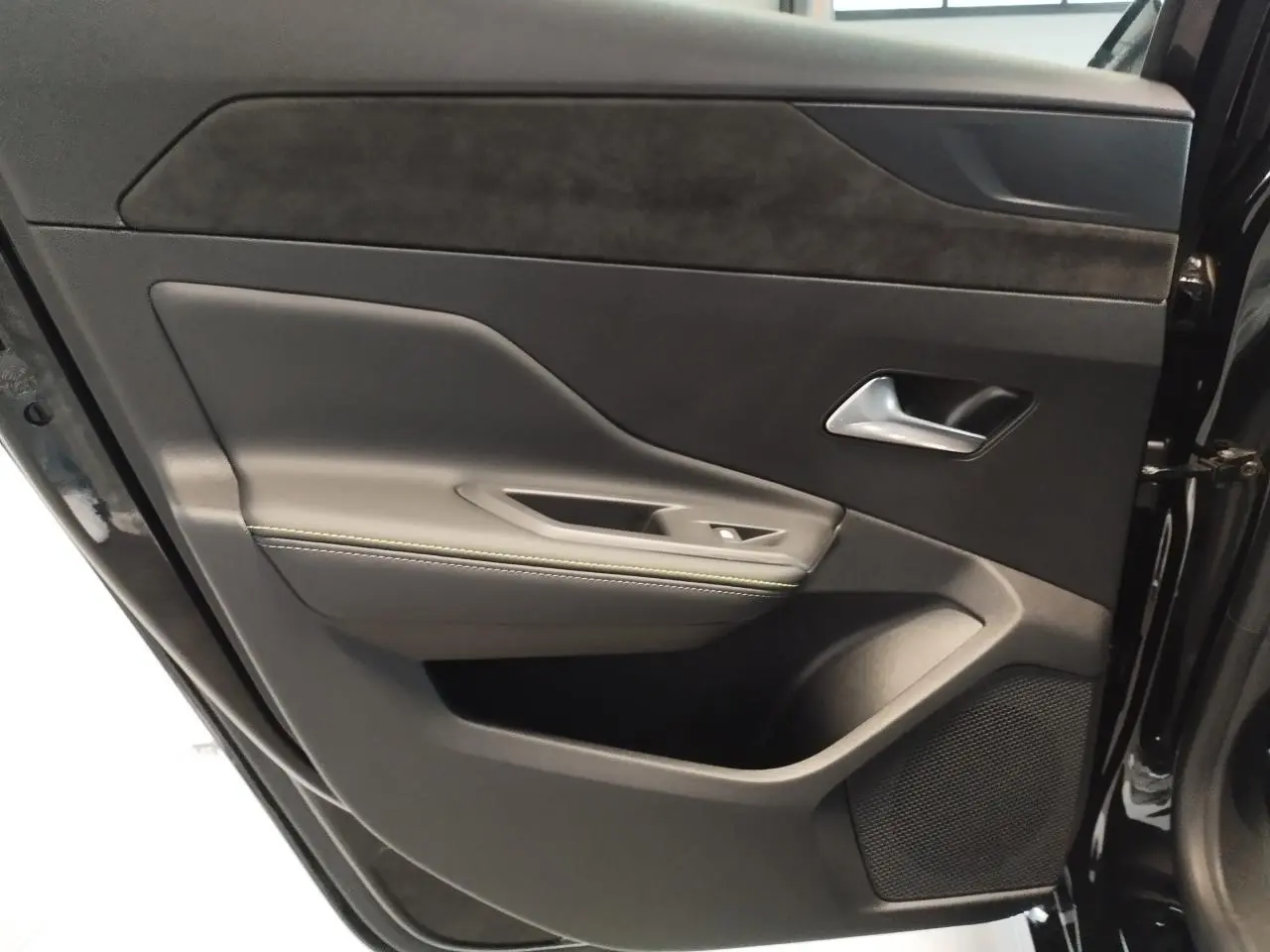Porte arrière droite ouverte de la Peugeot 308 noire, avec garniture noire et surpiqûres vert Adamite visibles.