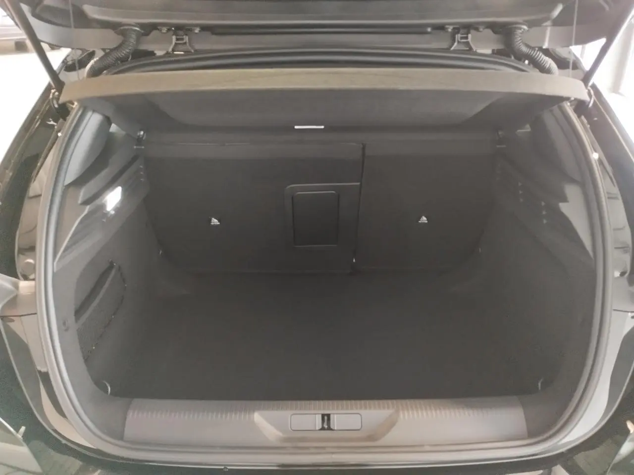 Coffre ouvert de la Peugeot 308 noire métallisée, vue arrière montrant l'espace de chargement vide et les finitions intérieures.