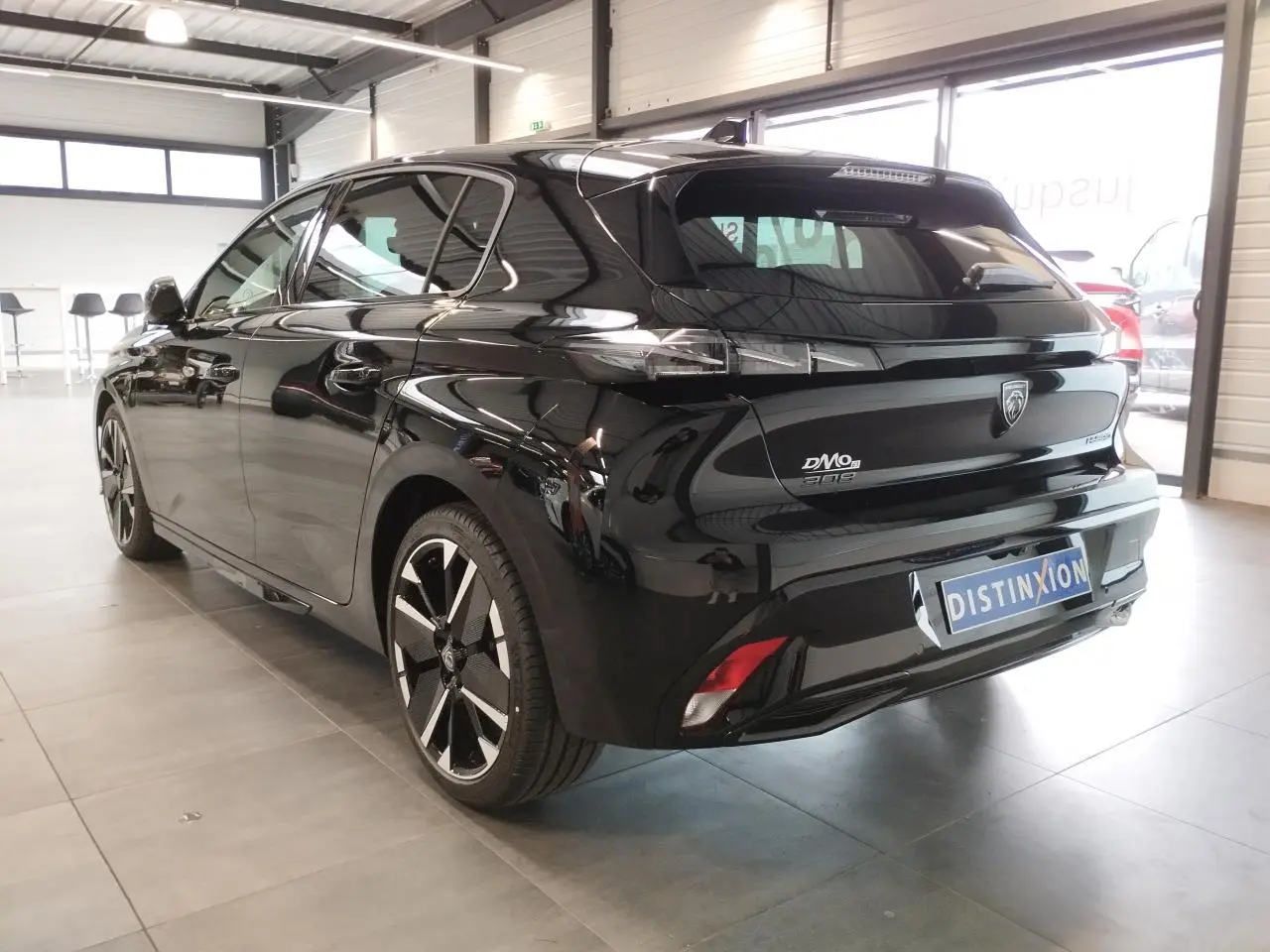 Vue 3/4 arrière droite d'une Peugeot 308 noire métal avec jantes alliage bi-tons et feux arrière LED 3 griffes.