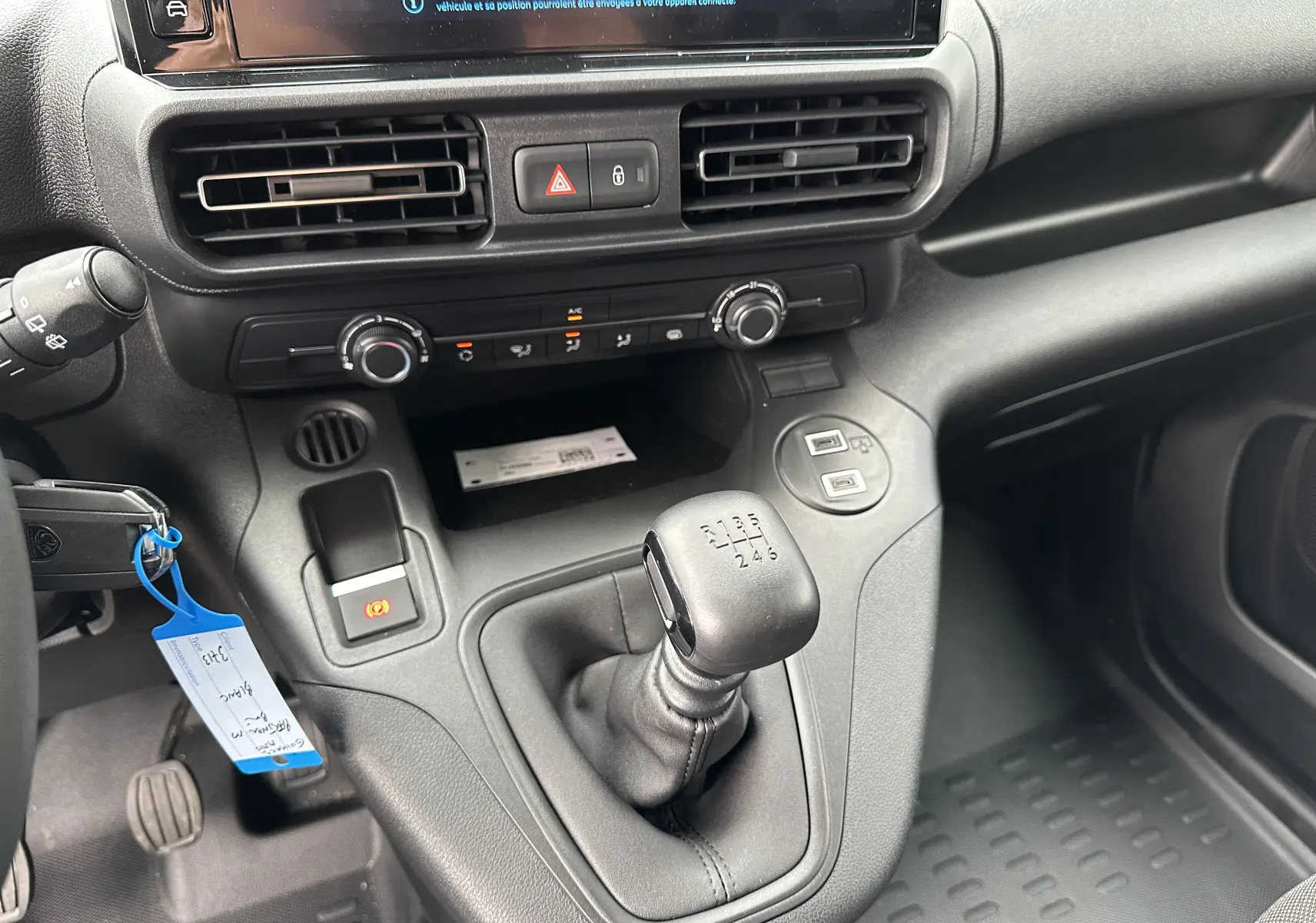 Intérieur du Peugeot Partner Fourgon 2024 montrant la console centrale avec levier de vitesse manuel et commandes de climatisation.
