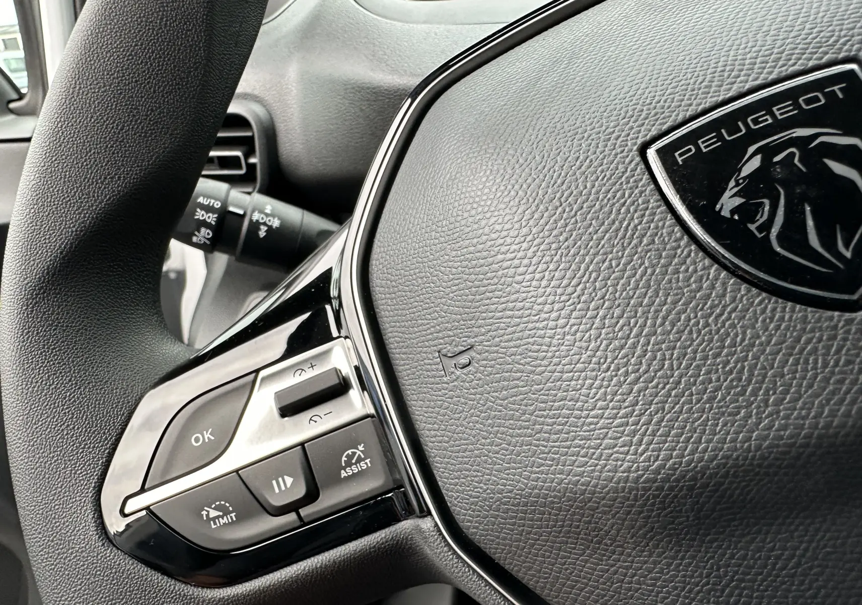 Gros plan sur le volant noir du Peugeot Partner Fourgon 2024 avec commandes intégrées et logo lion visible.