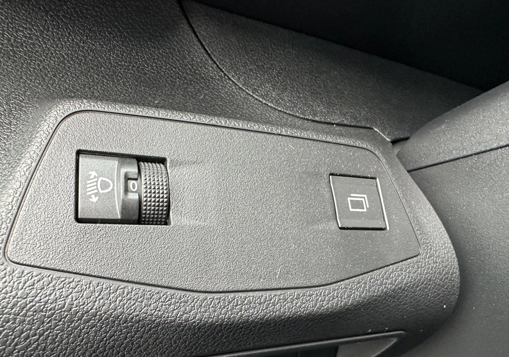 Gros plan sur les commandes de réglage des phares et du tableau de bord du Peugeot Partner Fourgon blanc 2024.