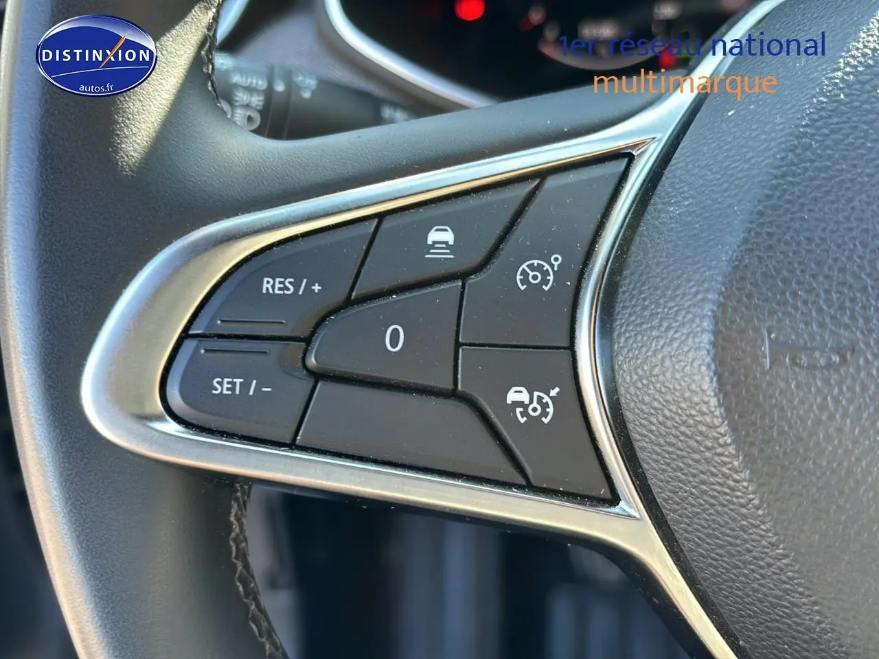 Gros plan sur les commandes de régulateur de vitesse du volant textile enduit gris/noir d'une Renault Clio V gris pizarra.