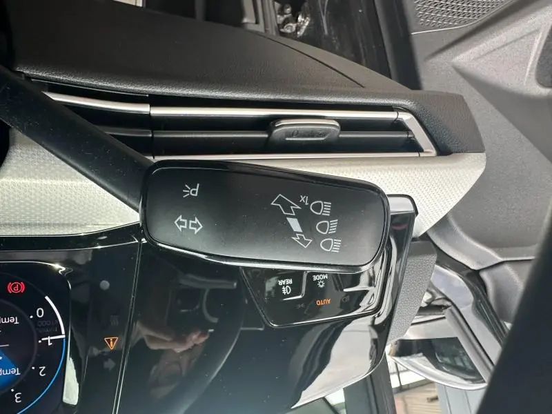 Gros plan sur la commande de clignotants et phares à gauche du volant dans l’habitacle noir nacré d’une Volkswagen Golf 2024.
