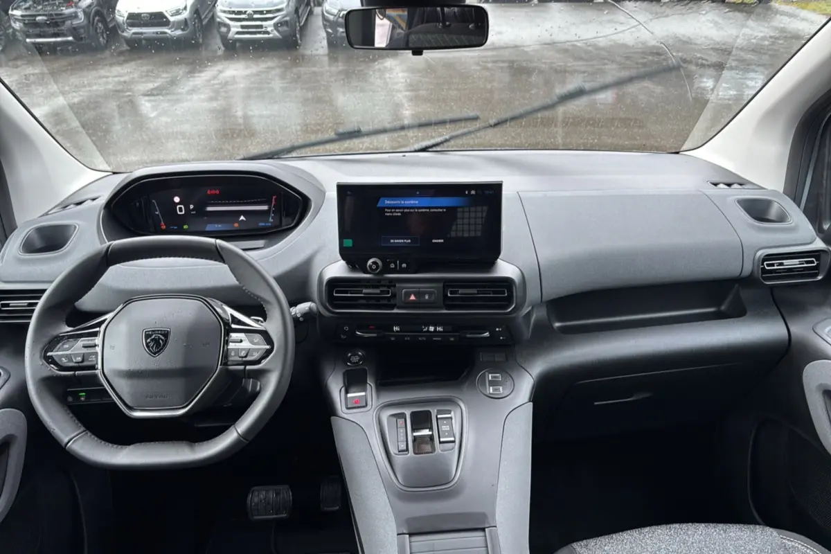 Vue intérieure avant du Peugeot Rifter 2026 gris Artense, avec tableau de bord numérique et écran tactile central.