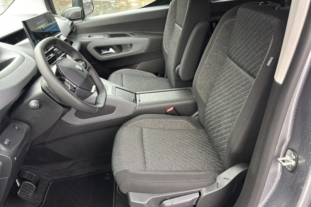 Intérieur avant du Peugeot Rifter gris artense, vue côté conducteur montrant sièges tissu et tableau de bord moderne.