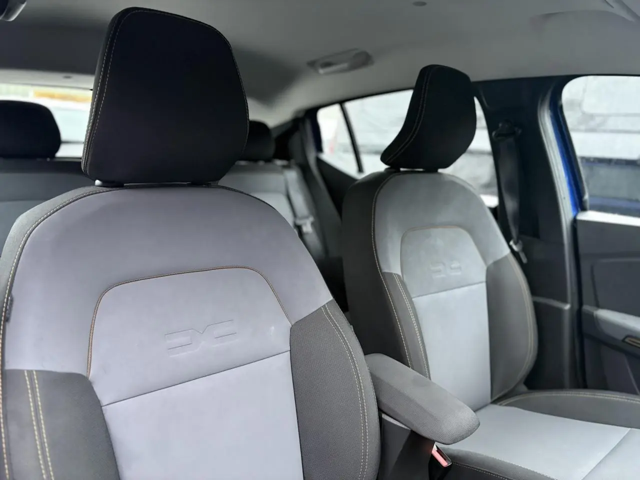 Vue intérieure des sièges avant gris clair et noir avec surpiqûres contrastantes dans une Dacia Sandero Stepway Bleu Iron.