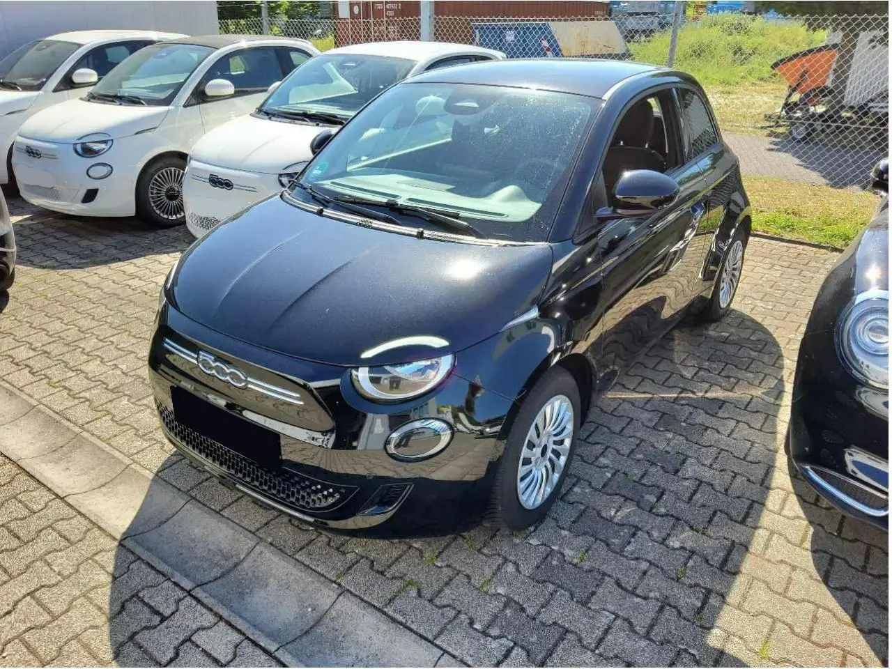 Fiat 500 électrique noire vue 3/4 avant droit, avec phares ronds et calandre chromée distinctive.