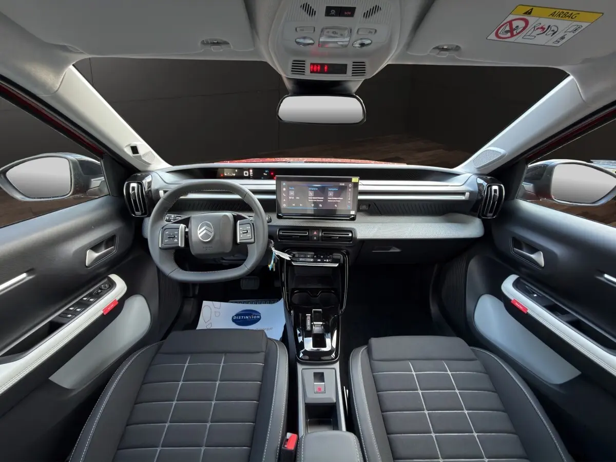 Vue intérieure avant de la Citroën C3 rouge 2026, tableau de bord moderne avec écran tactile et volant cuir multifonctions.