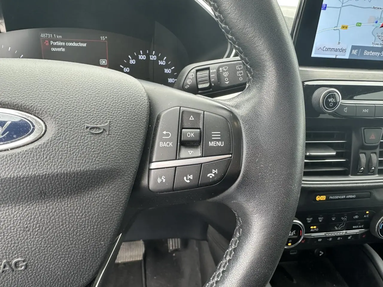 Gros plan sur le volant multifonction et le tableau de bord du Ford Kuga gris solaire avec écran tactile et commandes intégrées.