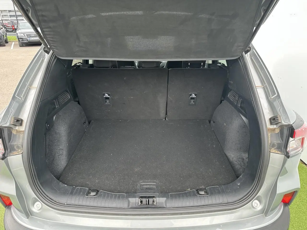 Coffre ouvert vu de l'arrière d'un Ford Kuga gris solaire, montrant un espace de chargement vide et propre.