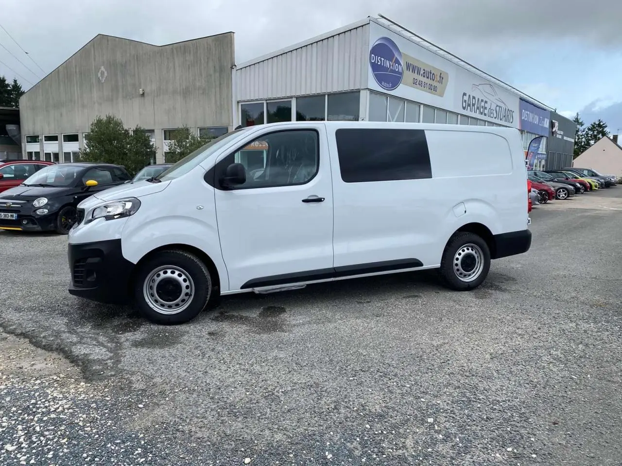 Peugeot Expert Fourgon blanc vu de profil côté gauche, stationné devant un garage avec porte coulissante.