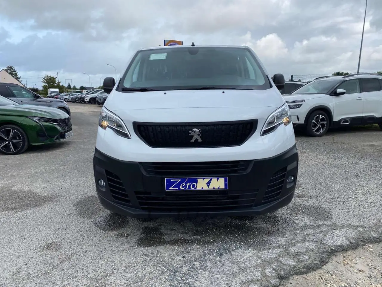 Vue frontale d'un Peugeot Expert Fourgon blanc 2023 avec calandre noire et plaque Zero KM visible.