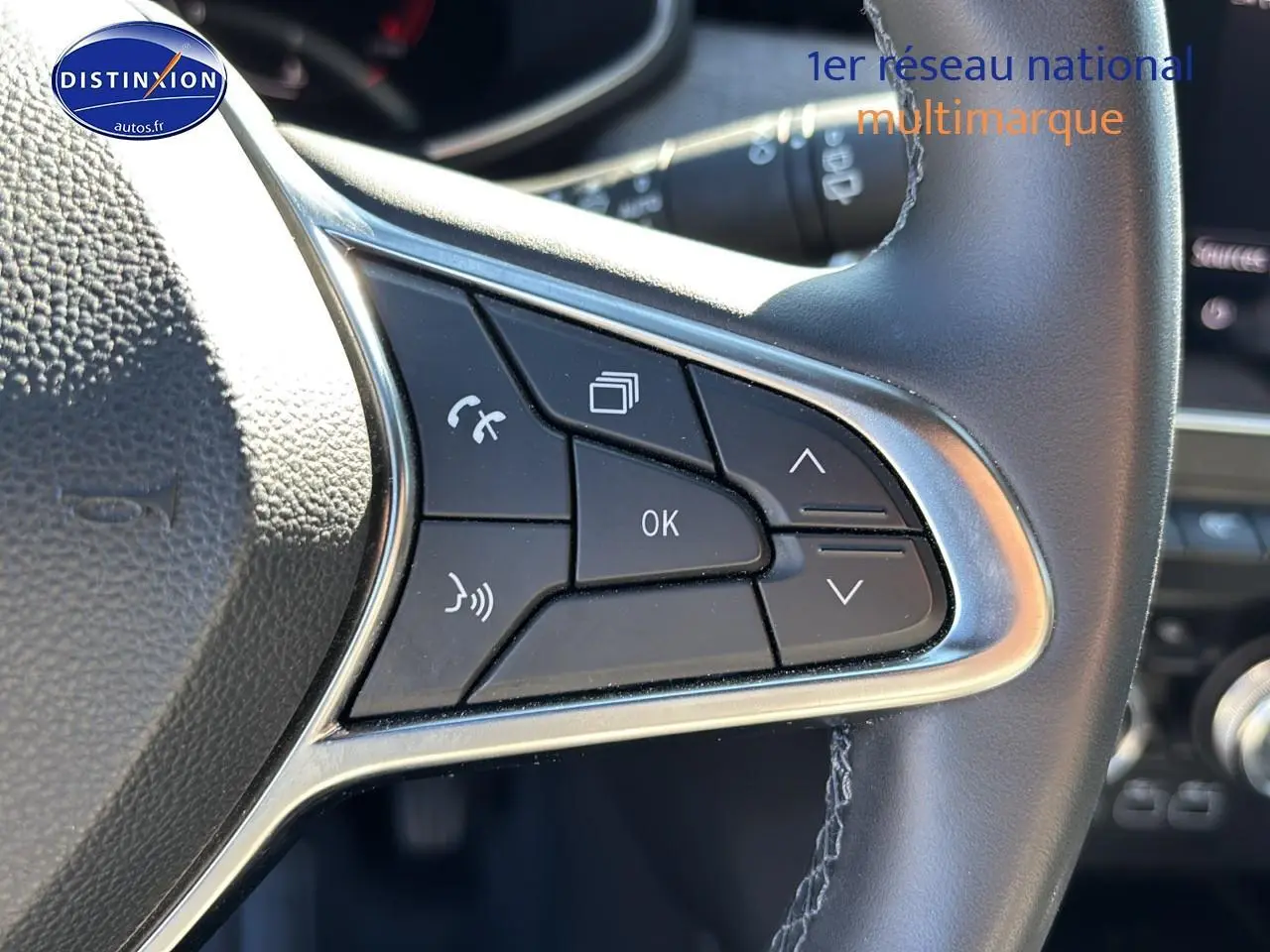 Gros plan sur les commandes gauche du volant textile enduit gris/noir de la Renault Clio V gris pizarra 2024.