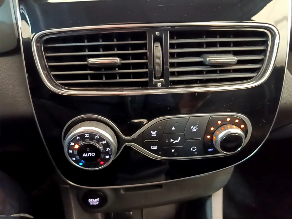Gros plan sur la console centrale noire de la Renault Clio Business, montrant les commandes de climatisation et la ventilation.