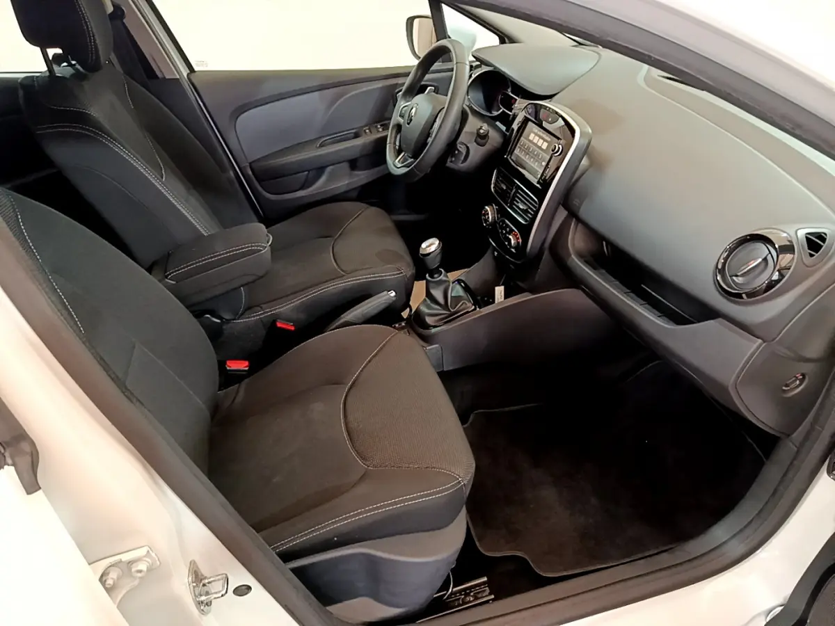Intérieur de la Renault Clio Business TCe 90 blanc, vue côté conducteur montrant sièges noirs et tableau de bord tactile.