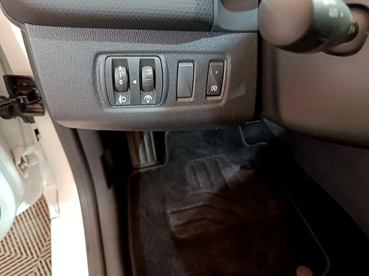 Vue intérieure côté gauche du tableau de bord de la Renault Clio Business TCe 90 blanche, avec commandes d'éclairage et réglages.