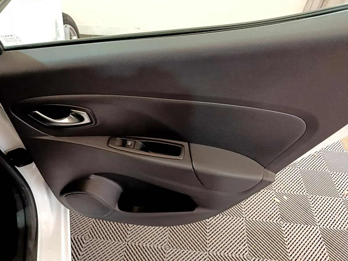 Vue rapprochée de la porte côté gauche d'une Renault Clio Business blanche, montrant la poignée et les commandes de fenêtre.