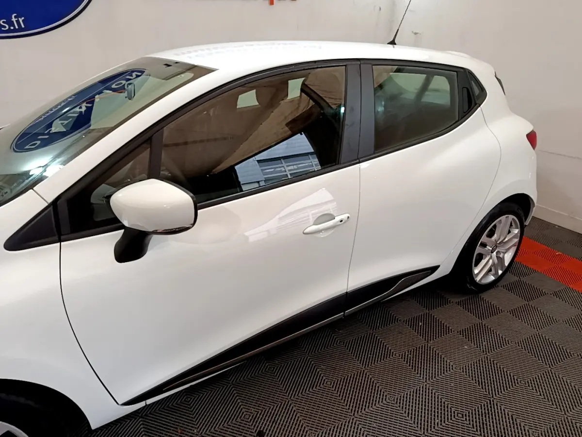 Profil côté gauche d'une Renault Clio Business TCe 90 blanche, avec rétroviseur et jante alliage visibles.