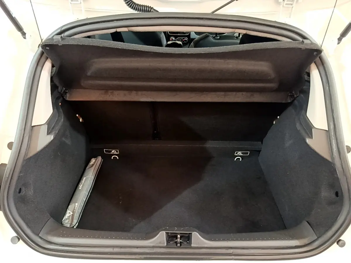 Coffre ouvert de la Renault Clio Business TCe 90 blanche, vue arrière montrant l'espace de rangement noir et la tablette de coffre.