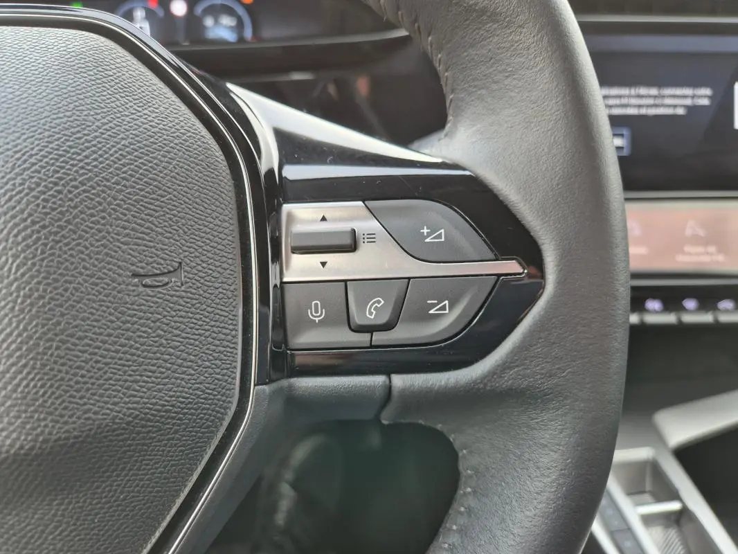 Gros plan sur les commandes au volant à droite du Peugeot 308 2024, intérieur noir avec affichage numérique en arrière-plan.