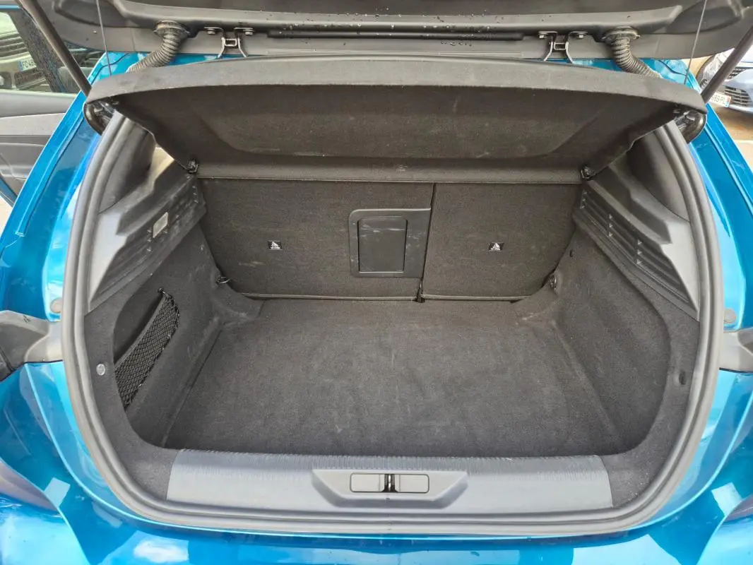 Coffre ouvert vu de l'arrière d'une Peugeot 308 bleu 2024, montrant un espace de chargement propre et spacieux.