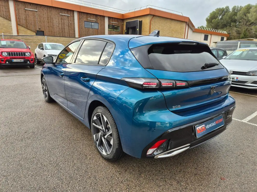 Vue 3/4 arrière droite d'une Peugeot 308 bleu 2024 avec jantes alliage et feux arrière LED distinctifs.
