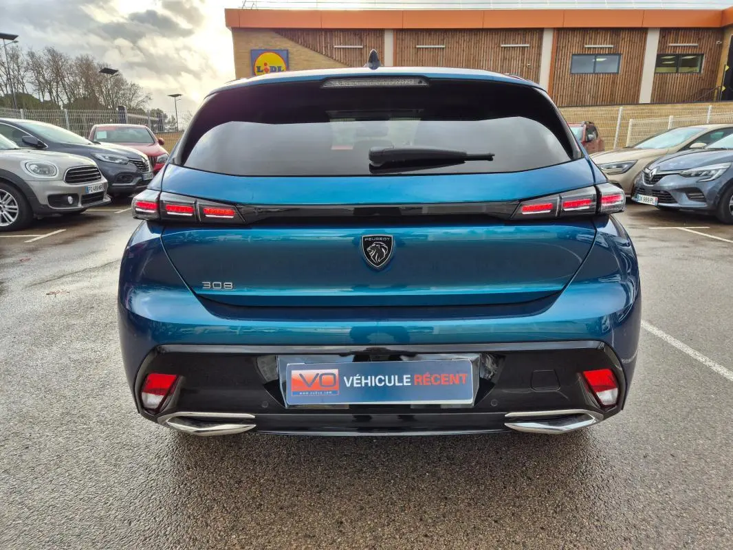 Vue arrière d'une Peugeot 308 bleu 2024 avec feux LED distinctifs et double sortie d'échappement chromée.