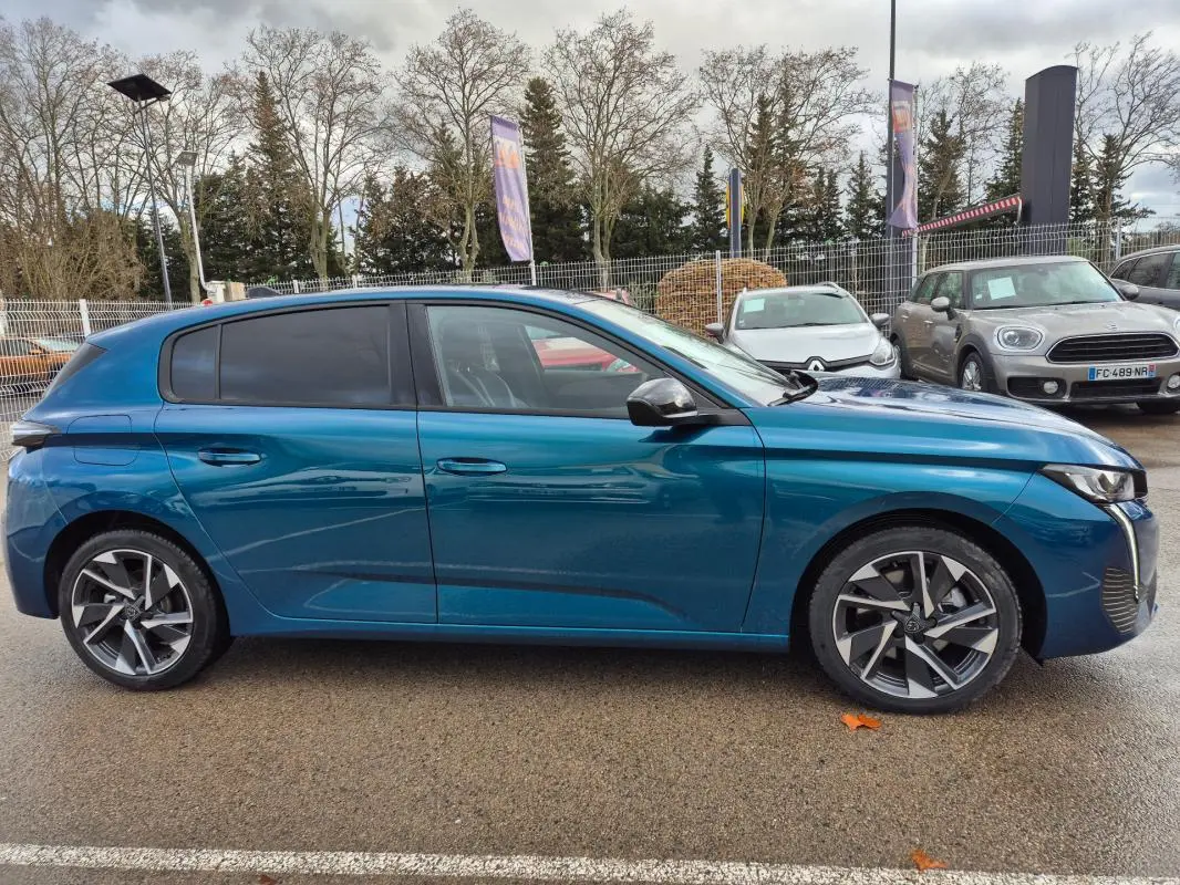Profil côté gauche d'une Peugeot 308 bleu 2024 avec jantes alliage 17 pouces et vitres teintées.