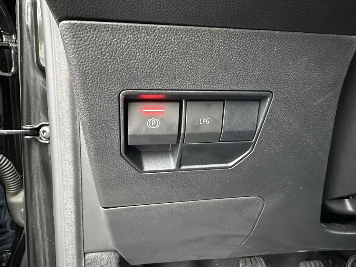 Gros plan sur les commandes du frein de stationnement électrique et du bouton GPL, tableau de bord noir du Dacia Duster 2025.