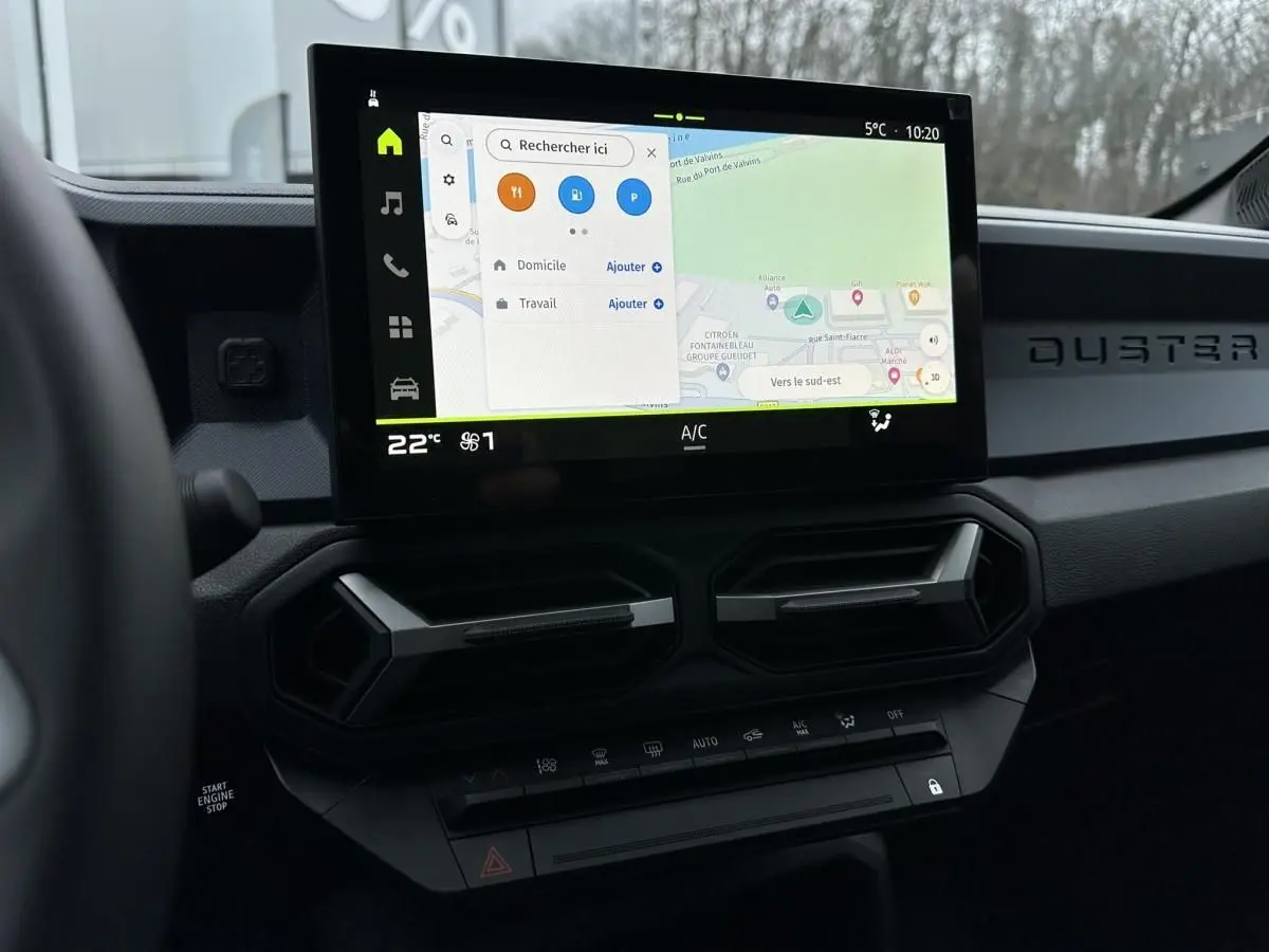 Vue intérieure du tableau de bord du Dacia Duster 2025 avec écran tactile central affichant la navigation.