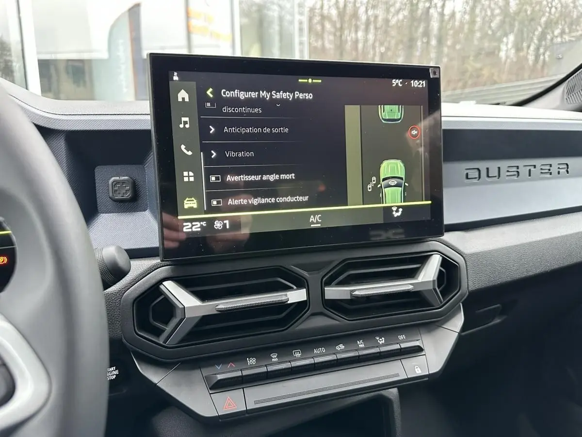 Vue intérieure du tableau de bord du Dacia Duster 2025 noir, avec écran tactile central et aérateurs hexagonaux.