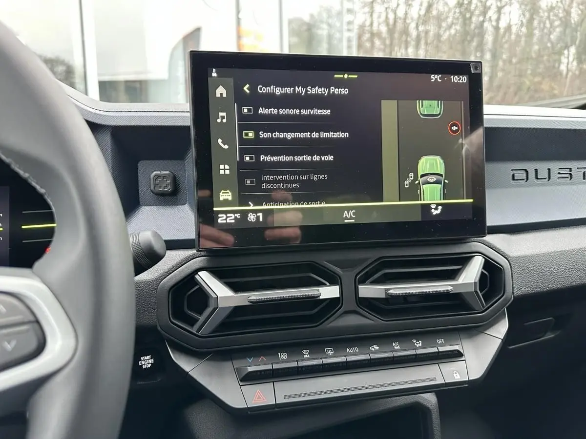 Vue intérieure du tableau de bord du Dacia Duster noir 2025, avec écran tactile central affichant les aides à la conduite.