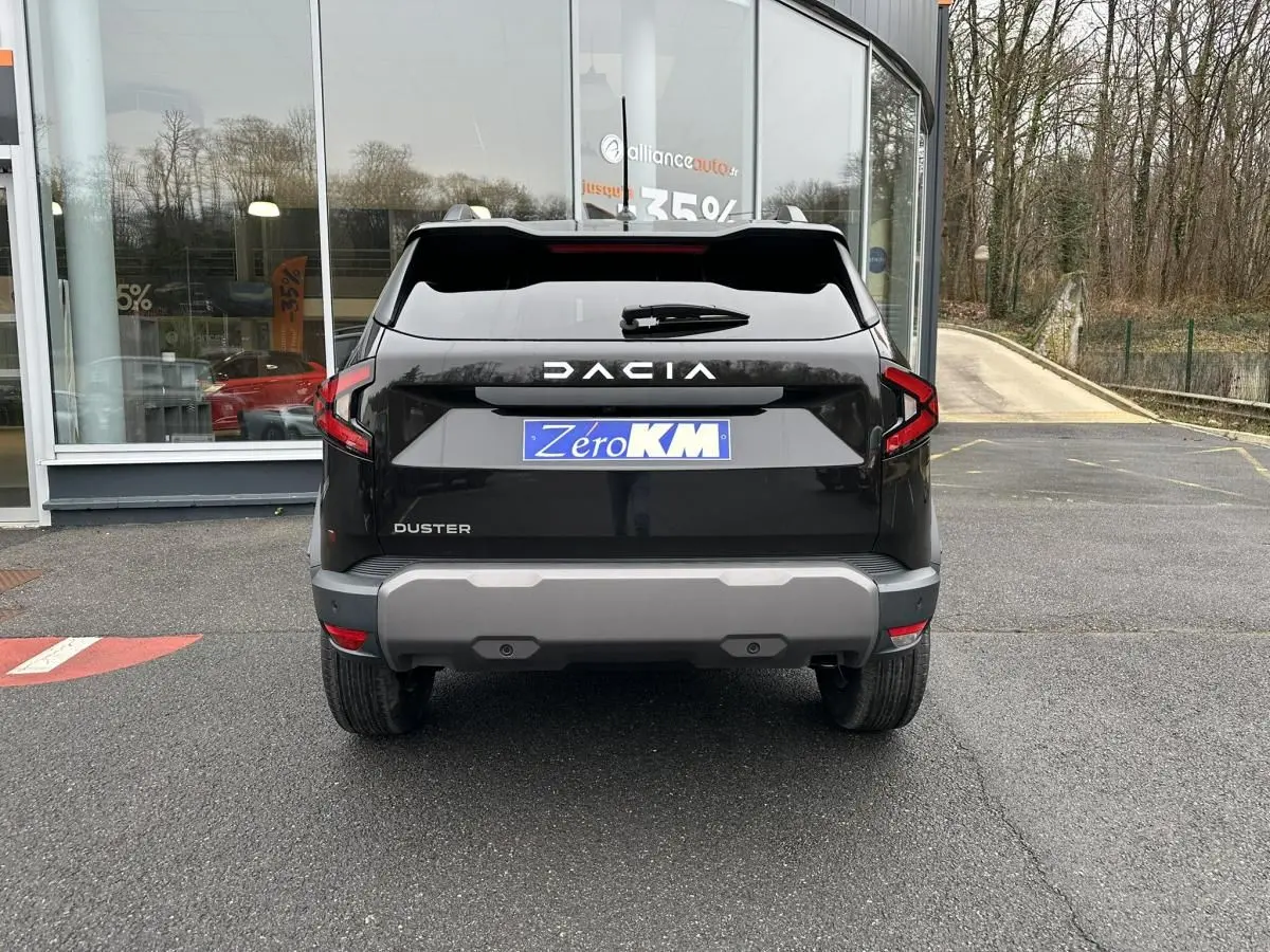 Vue arrière d'un Dacia Duster noir 2025 avec barres de toit et feux arrière en forme de C.