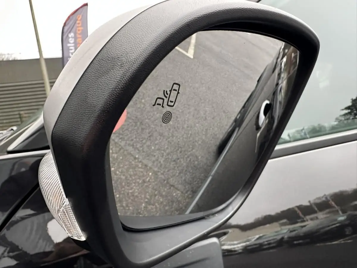 Rétroviseur extérieur côté gauche du Dacia Duster noir 2025 avec indicateur d'angle mort intégré.