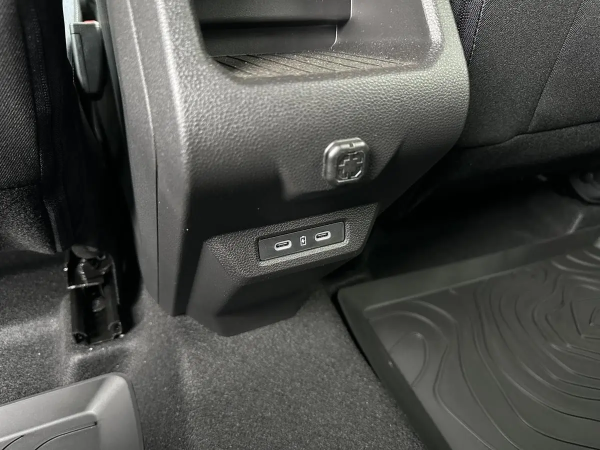 Prise USB type C arrière sur console centrale noire du Dacia Duster 2025, vue rapprochée côté droit arrière.