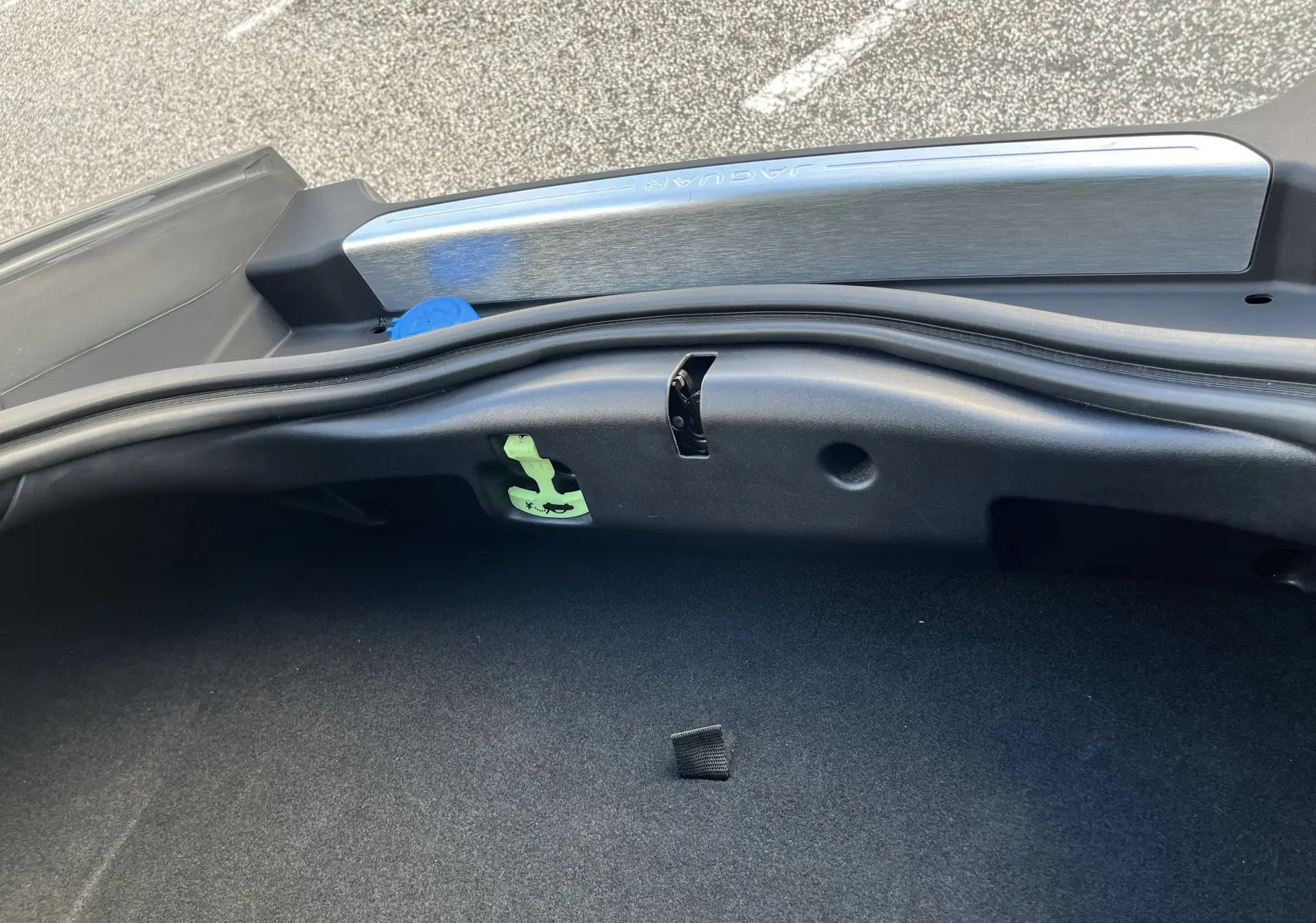 Vue rapprochée de l'intérieur du coffre d'une Jaguar F-TYPE gris Corris, montrant la garniture et la poignée de déverrouillage.