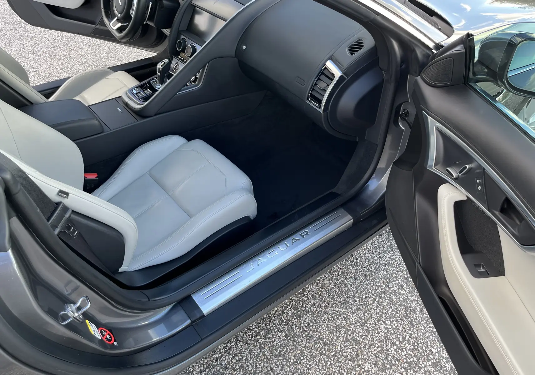 Vue intérieure côté passager d'une Jaguar F-TYPE II Coupe 2.0T 2018 gris Corris avec sièges sport cuir clair et tableau de bord noir.