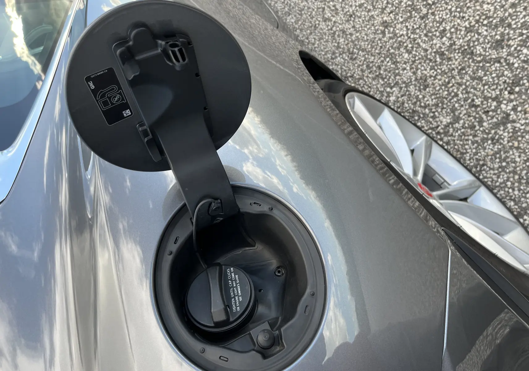 Détail de la trappe à carburant ouverte côté gauche sur Jaguar F-TYPE II Coupé 2.0T 2018 couleur Corris Grey.
